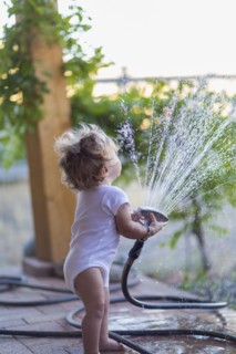 Caucasian baby boy playing with hose on patio