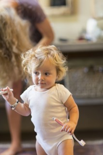 Caucasian baby boy holding toothbrush in bathroom