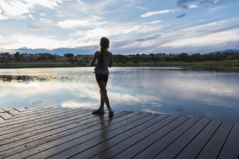 Caucasian girl standing on wooden deck near lake