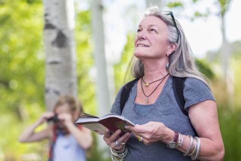 Caucasian senior woman carrying guidebook in forest