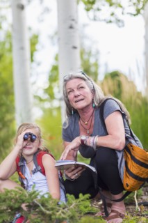 Caucasian grandmother and granddaughter using binoculars while hiking
