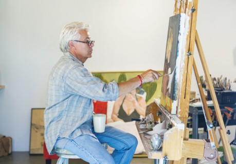 Older Hispanic artist painting in studio