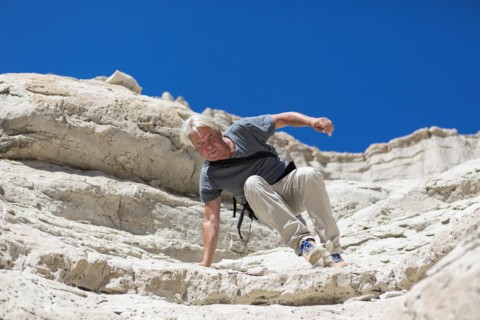 Older Caucasian man climbing rock formations