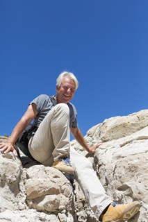 Older Caucasian man climbing rock formations