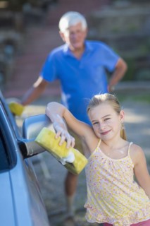 Caucasian grandfather and granddaughter washing car outdoors