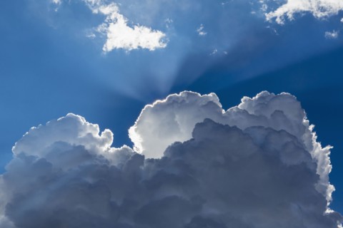 Sunbeams shining through clouds in blue sky