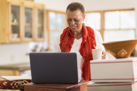 Older mixed race woman using laptop in home office
