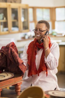 Older mixed race woman talking on telephone in home office