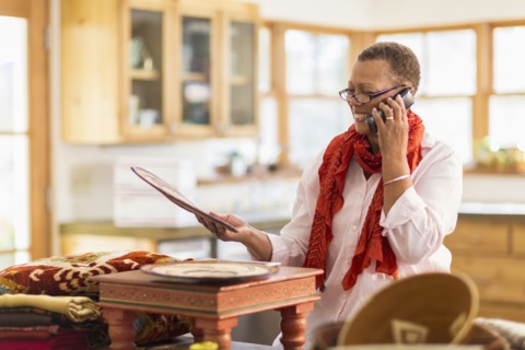 Older mixed race woman talking on telephone in home office