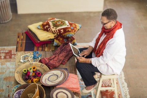 Older mixed race woman using digital tablet in home office