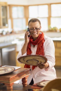Older mixed race woman talking on telephone in home office