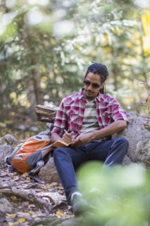 Mixed race hiker writing in forest