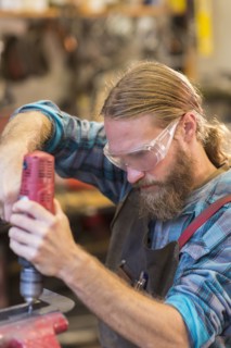 Caucasian craftsman drilling in workshop