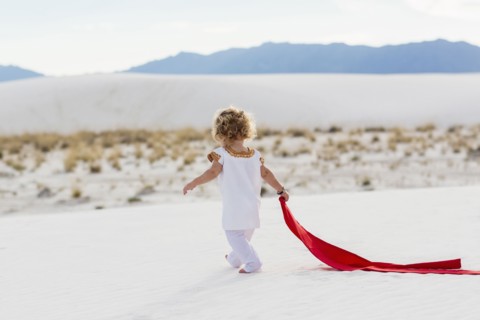 Caucasian boy playing with scarf on sand dune