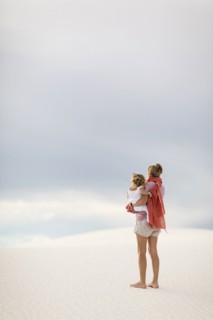 Caucasian mother holding son on sand dune