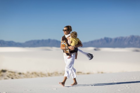 Caucasian mother carrying son on sand dune