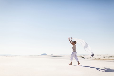 Caucasian woman playing with scarf on sand dune