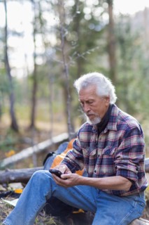 Caucasian hiker using cell phone in forest