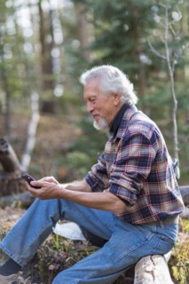Caucasian hiker using cell phone in forest