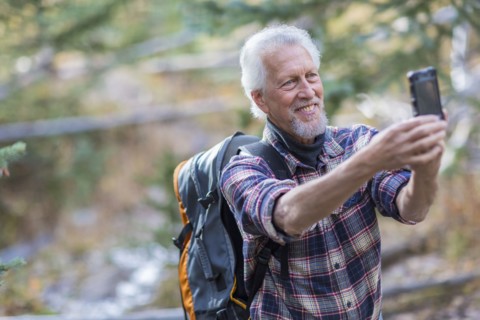 Caucasian hiker taking cell phone photograph in forest