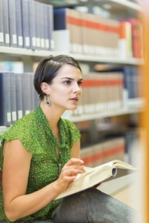 Mixed race student reading book in library