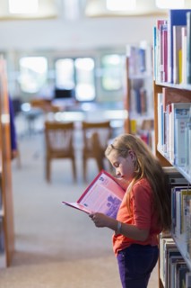 Caucasian student reading book in library