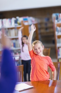 Student raising her hand in library