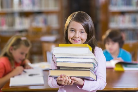 Student carrying stack of books in library