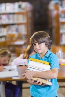 Student carrying stack of books in library