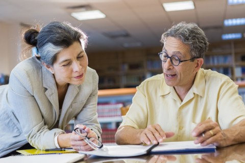 Teacher helping adult student in library