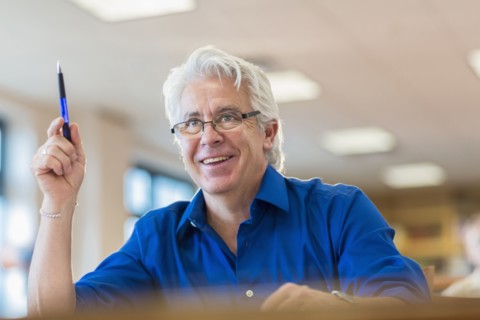 Hispanic adult student raising his hand in class