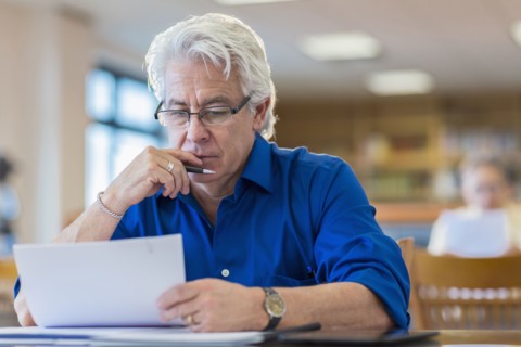 Man reading paperwork in library