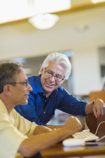 Teacher helping adult student use computer in library