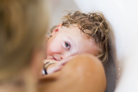 Caucasian mother nursing baby son in bath