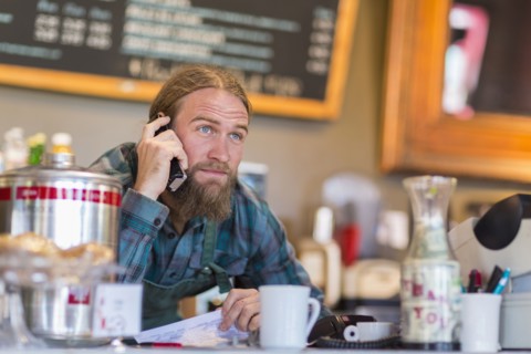 Caucasian server using telephone in cafe