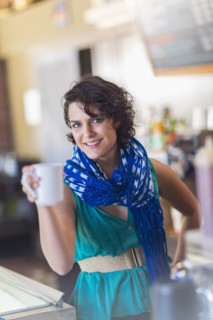 Mixed race woman holding cup of coffee in cafe