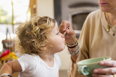 Caucasian mother feeding baby son in high chair