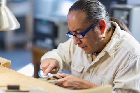 Close up of Native American jeweler working in studio
