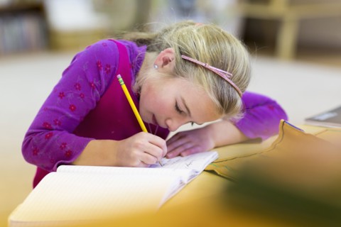 Caucasian girl writing in classroom