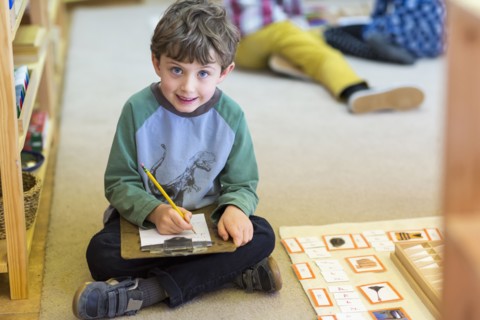 Smiling boy writing in classroom
