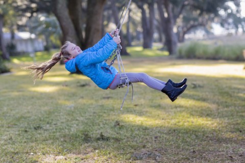 Caucasian girl playing on swing