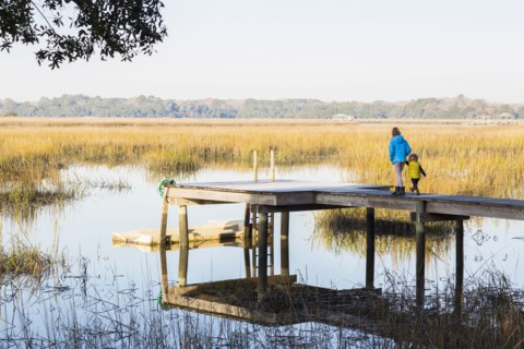 Caucasian children walking on wooden dock over lake