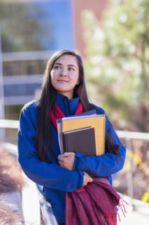 Mixed race student holding books on campus