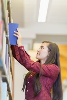 Mixed race student selecting book in library