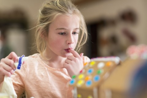 Caucasian girl decorating gingerbread house