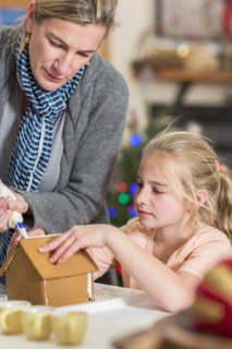 Caucasian mother and daughter decorating gingerbread house