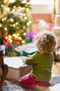 Caucasian baby boy opening presents near Christmas tree