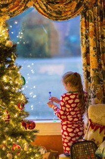 Caucasian girl opening present near Christmas tree