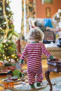 Caucasian baby boy playing with toys near Christmas tree