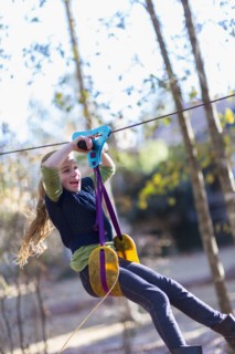 Caucasian girl zip lining in forest